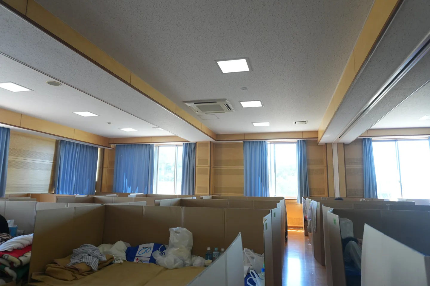 部屋の中に間仕切りと寝具、生活用品が並ぶ避難環境
